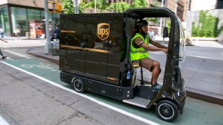 UPS worker Dyghton Anderson peddles an eQuad electric bike in a bicycle lane while delivering packages, in New York, Tuesday, July 14, 2022. Delivery giant UPS is going back to the future in its latest way to get packages to the doors of its millions of customers. The company is considering launching a fleet of pedal- and battery-powered cargo cycles for deliveries in some of the country's most congested cities.