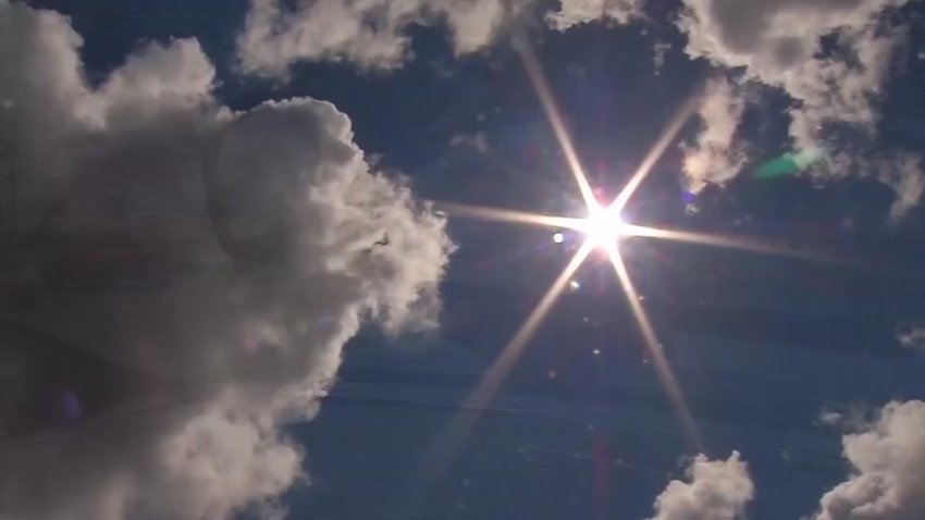 A generic image of a sun shining bright with minimal clouds in the sky.