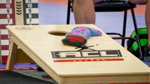 red and purple bean bags sit on a cornhole board with the "ACL" logo