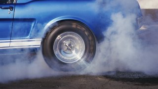 A car's spinning tires creating smoke