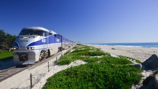 Amtrak Surfliner passenger train on tracks running alongside Pacific Ocean beaches near Santa Barbara on the west coast of California, USA (Photo by Nik Wheeler/Corbis via Getty Images)