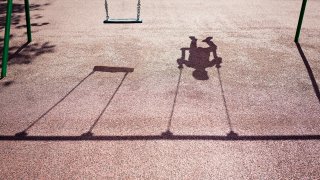 Shadow of a child on a playground swing.