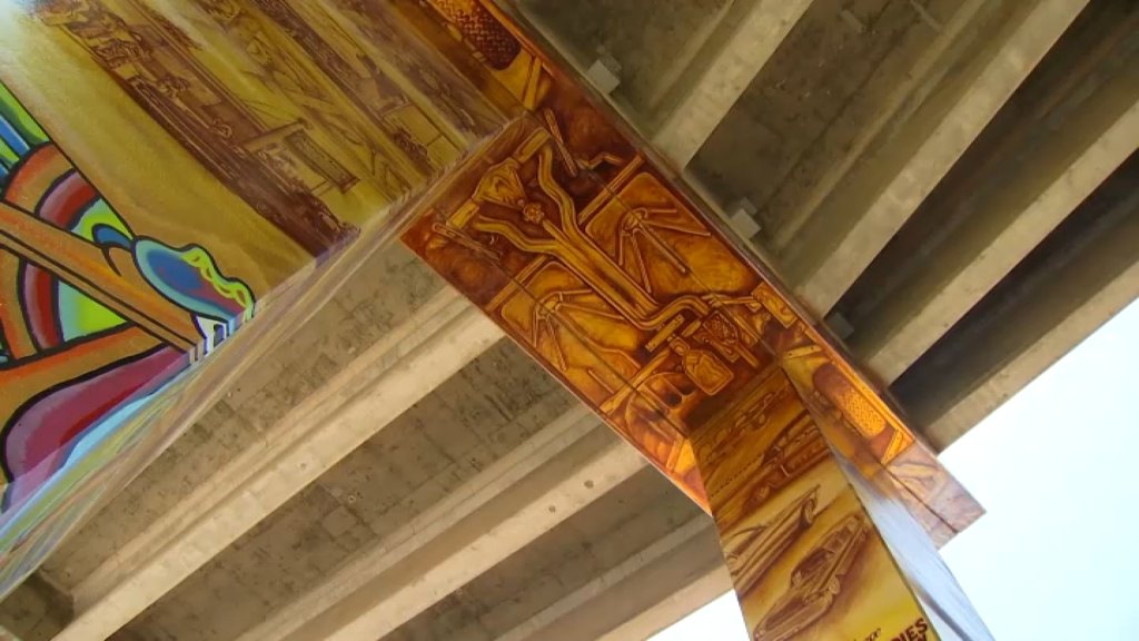 The undercarriage of a lowrider is painted on a beam of I-5 above Chicano Park. (July 15, 2022)