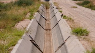 A dry irrigation canal runs between fields Thursday, Aug. 18, 2022, in Maricopa, Ariz.