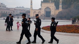 FILE - Uyghur security personnel patrol near the Id Kah Mosque in Kashgar in western China's Xinjiang region