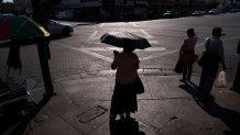 A pedestrian with an umbrella near MacArthur Park during a heatwave in Los Angeles, California, US, on Thursday, Sept. 1, 2022. After narrowing avoiding blackouts, California faces another bruising test of its power grid Thursday as a heat wave smothering the region builds, driving temperatures to dangerous levels. Photographer: Eric Thayer/Bloomberg via Getty Images