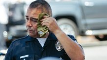 Los Angeles, CA - September 04: LAPD Officer Francisco Serrano wipes sweat off his face while working at the El Salvadorian Independence Day parade in over 100-degree heat on Sunday, Sept. 4, 2022 in Los Angeles, CA. (Wesley Lapointe / Los Angeles Times via Getty Images)