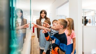 A group of young kids looking at various objects and images on display while on a field trip to a museum.