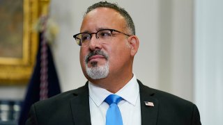 FILE - Education Secretary Miguel Cardona listens as President Joe Biden speaks about student loan debt forgiveness in the Roosevelt Room of the White House, Aug. 24, 2022, in Washington.