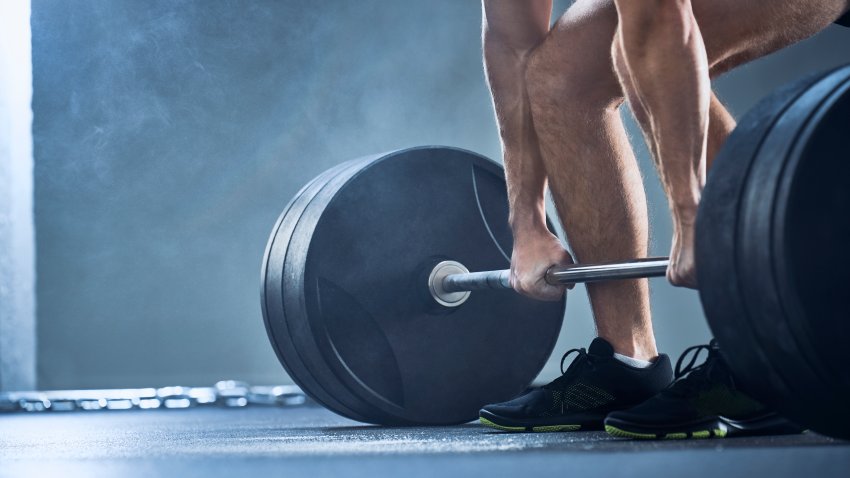 Close-up of man doing deadlift exercise at gym