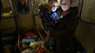 A woman holds her child inside a subway wagon in an underground metro station used as a bomb shelter in Kyiv.