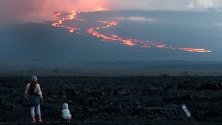 FILE - Spectators watch the lava flow down the mountain from the Mauna Loa eruption, Nov. 29, 2022, near Hilo, Hawaii.