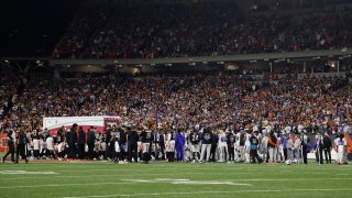 Buffalo Bills and Cincinnati Bengals players look on as Damar Hamlin #3 of the Buffalo Bills is treated by medical personnel