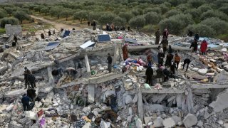 Civil defense workers and residents search through the rubble of collapsed buildings in the town of Harem near the Turkish border, Idlib province, Syria, Monday, Feb. 6, 2023. A powerful earthquake has caused significant damage in southeast Turkey and Syria and many casualties are feared. Damage was reported across several Turkish provinces, and rescue teams were being sent from around the country.