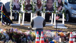 FILE – A person pauses to pay respects as portraits of the victims of a mass shooting at a gay nightclub are displayed at a makeshift memorial Nov. 22, 2022, near the scene in Colorado Springs, Colo.