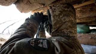 A Ukrainian infantryman with the 28th Brigade observes Russian positions from a front-line trench facing Russian troops on March 5, 2023, outside of Bakhmut, Ukraine.