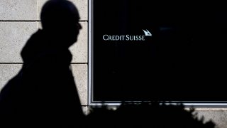 A man is seen in silhouette walking past a branch of Switzerland’s Credit Suisse bank in Vevey, western Switzerland, on March 15, 2023