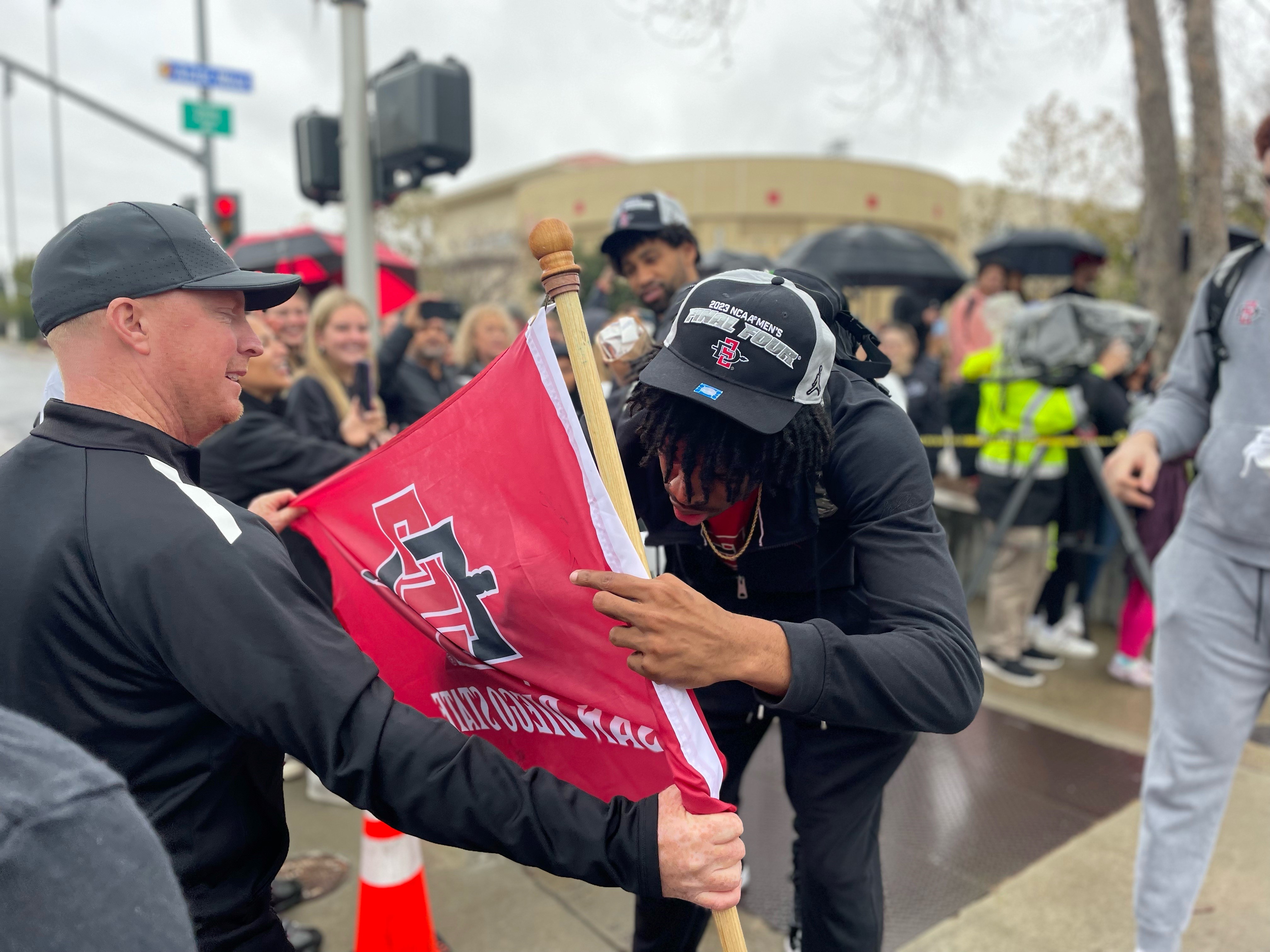 An SDSU player signs a fan's flag before they left to compete in the Final Four in Houston. Mar. 29, 2023