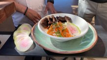 The Hawaiian Short Rib Bowl is a marinated beef short rib served with steamed rice, green onions, pickled daikon and carrot, furikake, and big wave sauce in the Kona Big Wave Patio in Section 227.