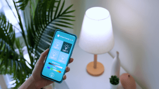 Someone holding a smartphone with an app to control home lighting