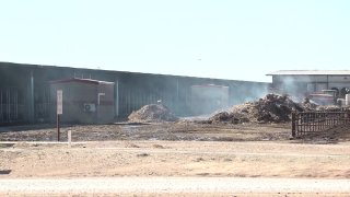 A barn and hay smolder at the Southfork Dairy Fire in Dimmit, Texas after an explosion and massive fire on April 11, 2023 critically injured one person and killed as many as 18,000 dairy cows.