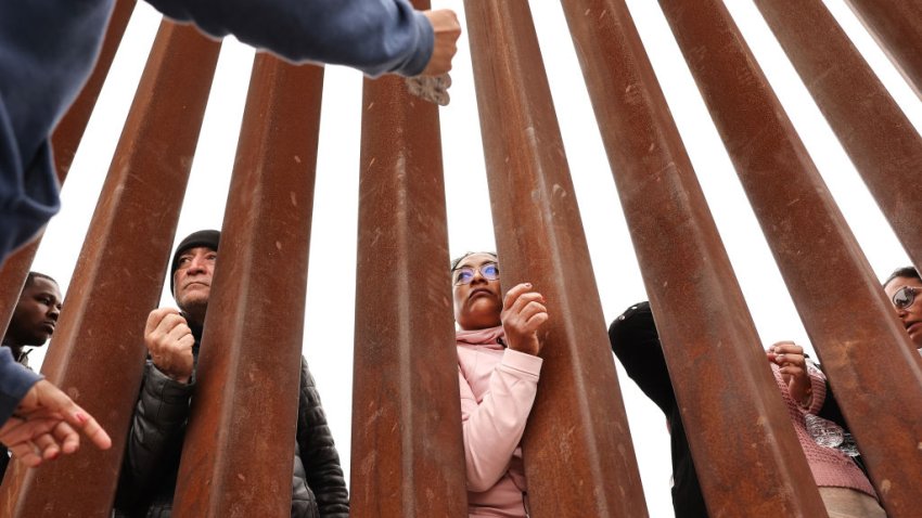 SAN DIEGO, CALIFORNIA - MAY 13: Immigrants seeking asylum in the U.S., who are stuck in a makeshift camp amongst border walls between the U.S. and Mexico, look through the border wall as volunteers offer assistance on the other side on May 13, 2023 as seen from San Diego, California. Some of the hundreds of migrants at the open-air camp have been waiting for days in limbo for a chance to plead for asylum. The U.S. government's Covid-era Title 42 policy, which for the past three years had allowed for the quick expulsion of irregular migrants entering the country, expired in the evening on May 11th.