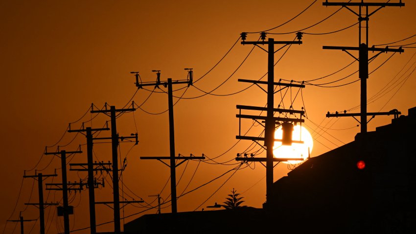 The sun sets behind power lines near homes during a heat wave in Los Angeles on Sept. 6, 2022.