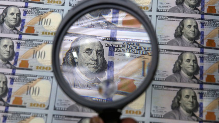 FILE – A sheet of uncut $100 bills is inspected during the printing process at the Bureau of Engraving and Printing Western Currency Facility in Fort Worth, Texas, on Sept. 24, 2013. More than $200 billion may have been stolen from two large pandemic-relief initiatives, according to a new estimates from a federal watchdog investigating federally funded programs designed to help small businesses survive the worst public health crisis in more than a hundred years.