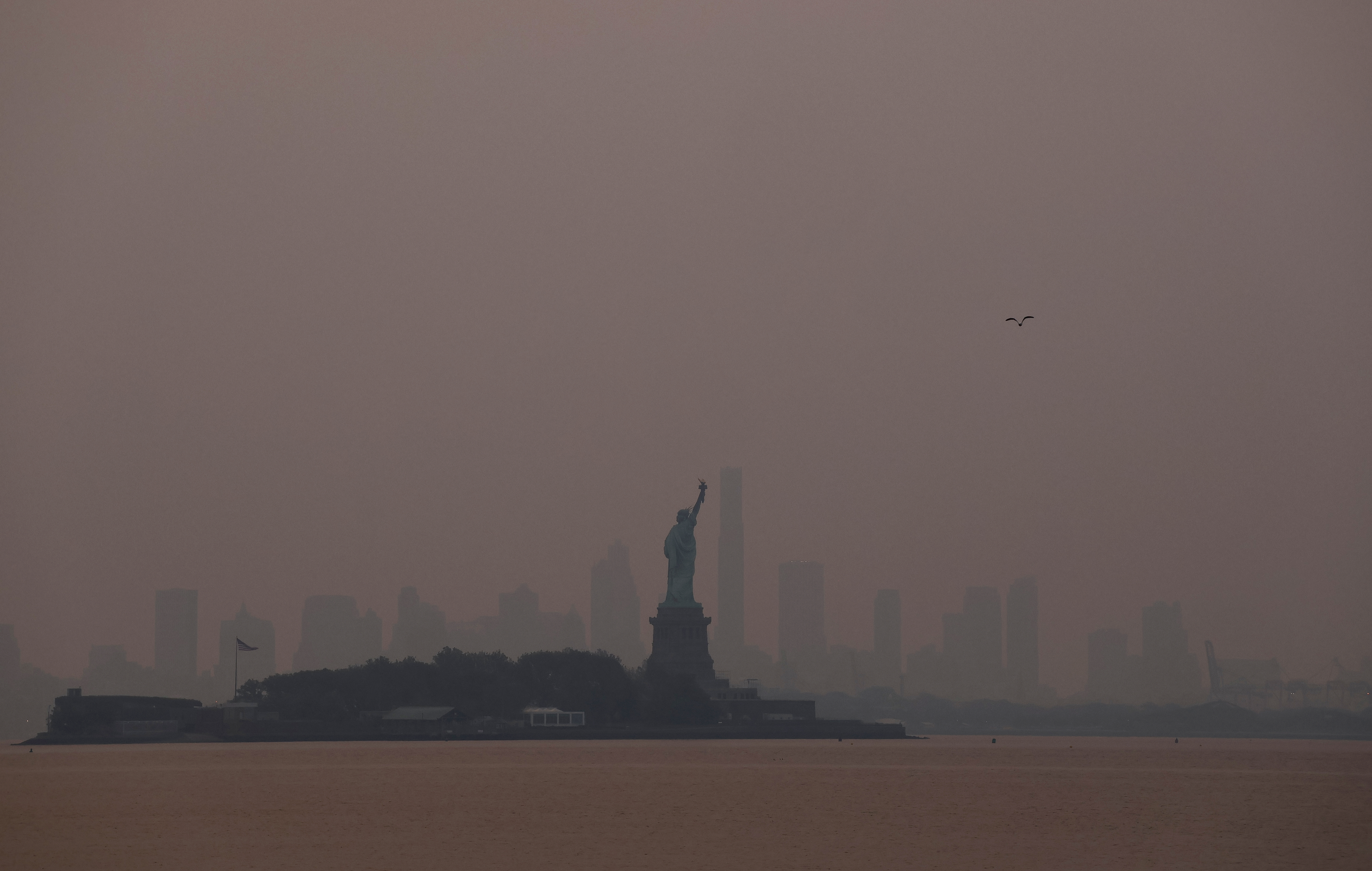 Smoke shrouds the skyline of Brooklyn behind the Statue of Liberty as the sun rises in New York City on June 7, 2023, as seen from Jersey City, New Jersey.  (Gary Hershorn/Getty Images)