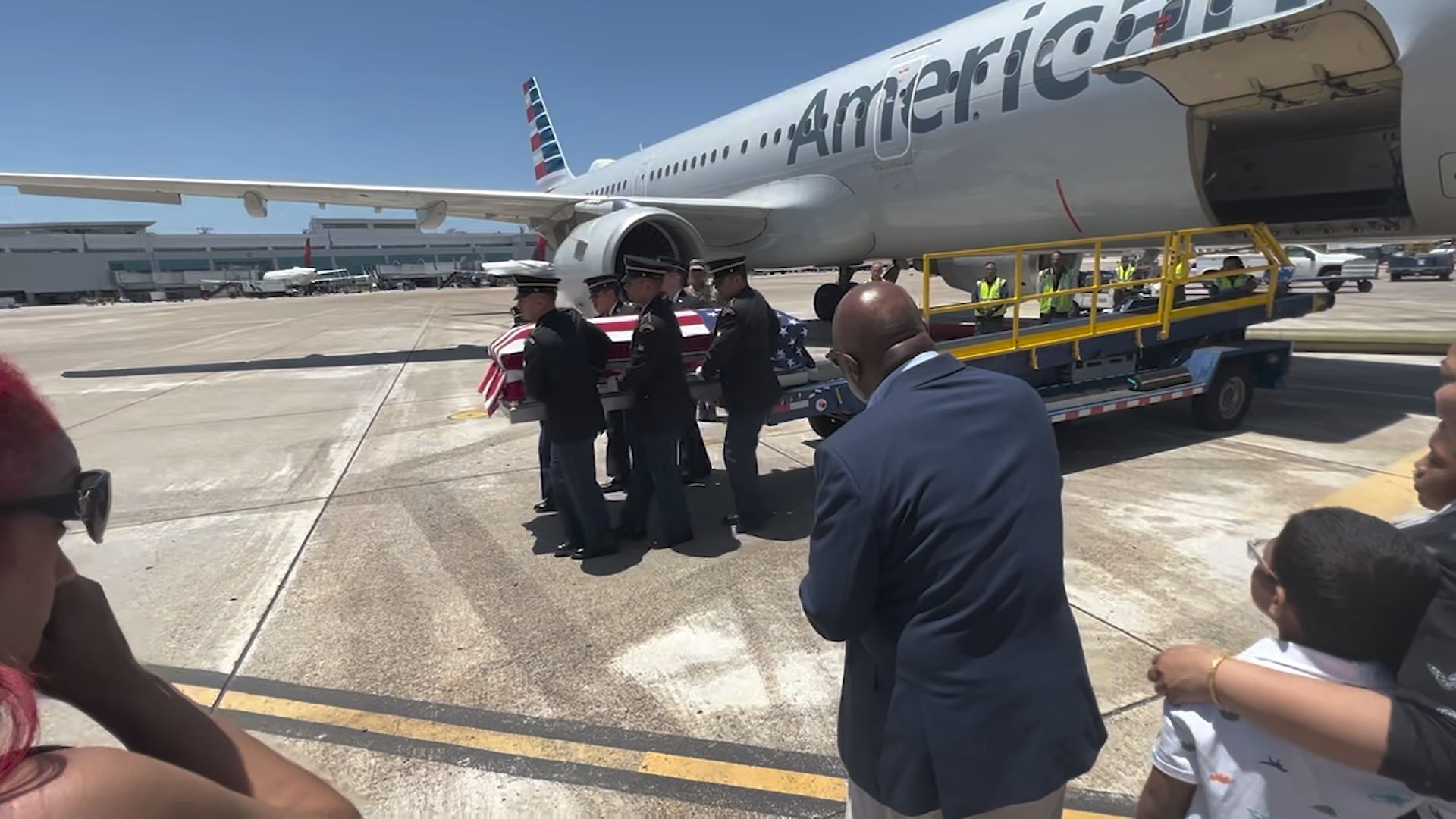 Flag-draped casket carried off an airplane