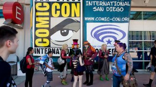 Visitors and cosplayers at a poster at San Diego Comic-Con.