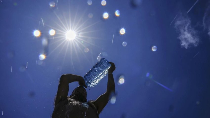 A person drinks water under a hot sun.