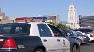 A Los Angeles Police Department patrol car with City Hall in the background.