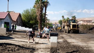 Residents and municipal workers clear out mud from a neighborhood in Cathedral City, Calif.