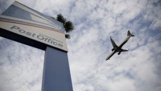 U.S. Postal Service signage stands as a Delta Air Lines Inc. aircraft lands at Los Angeles International Airport (LAX) in Los Angeles, California, U.S., on Monday, Aug. 17, 2020.