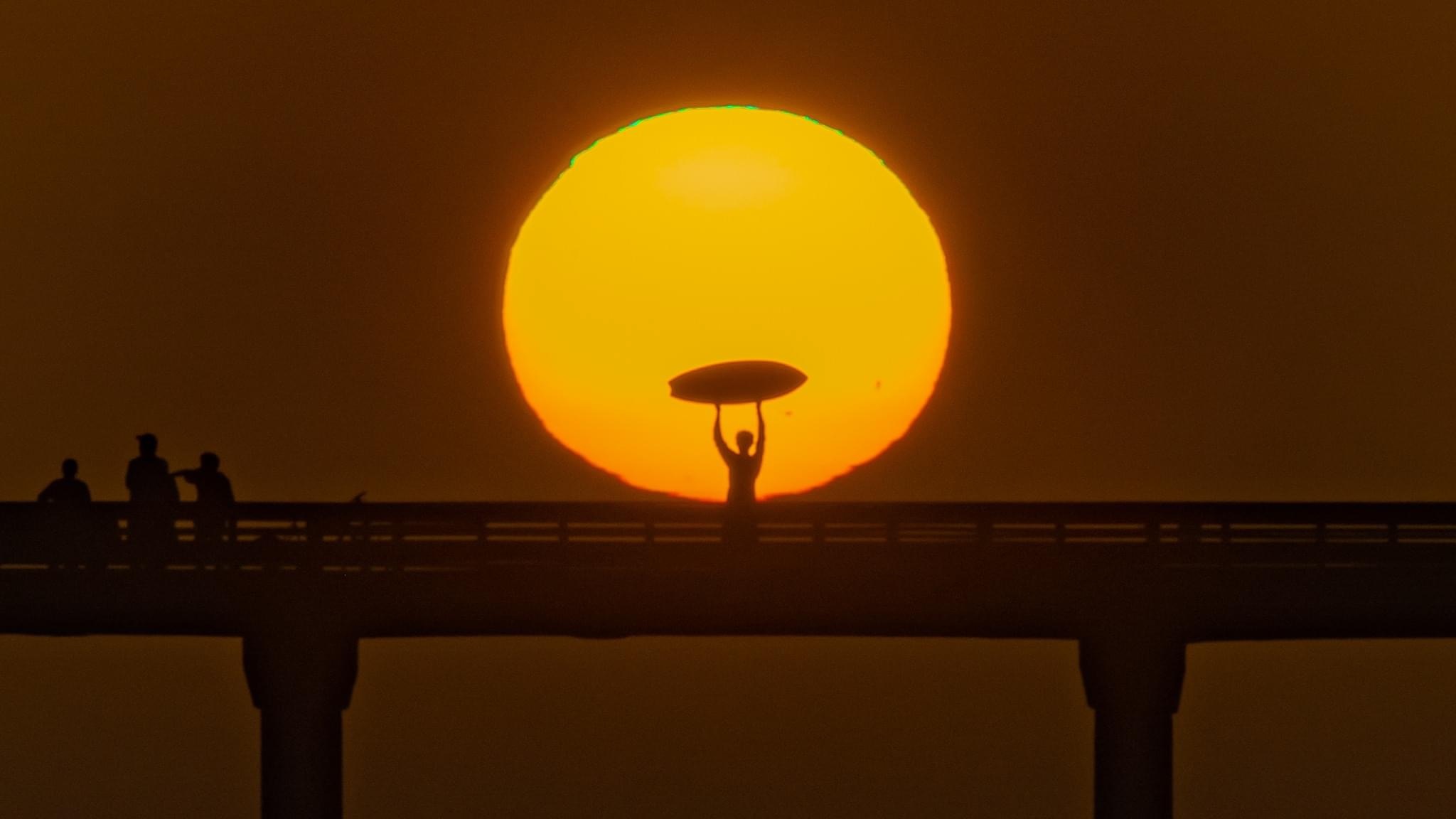 Surfista posa en Ocean Beach Pier durante la puesta de sol con la superluna del fotógrafo Jim Grant.