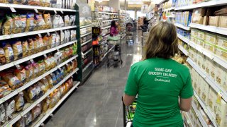 A shopper for Instacart navigates through the aisles as she shops for a customer.