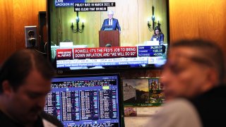 Federal Reserve Chairman Jerome Powell’s speech is seen on a television screen as traders work on the New York Stock Exchange floor during morning trading on August 25, 2023 in New York City.