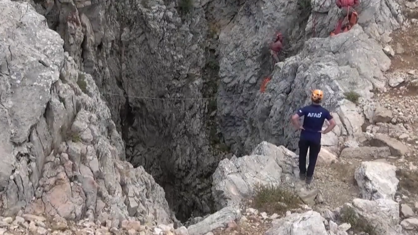 rescue worker stands in front of deep cave