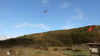 A helicopter airlifting the man off the cliffside after a hang gliding crash on Black Mountain. (Photo courtesy of San Diego Fire-Rescue Department)