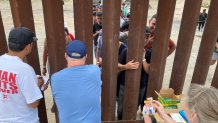 Humanitarian activists distribute snacks and other goods to asylum-seeking migrants at the U.S.-Mexico border south of San Diego on Sept. 12, 2023.