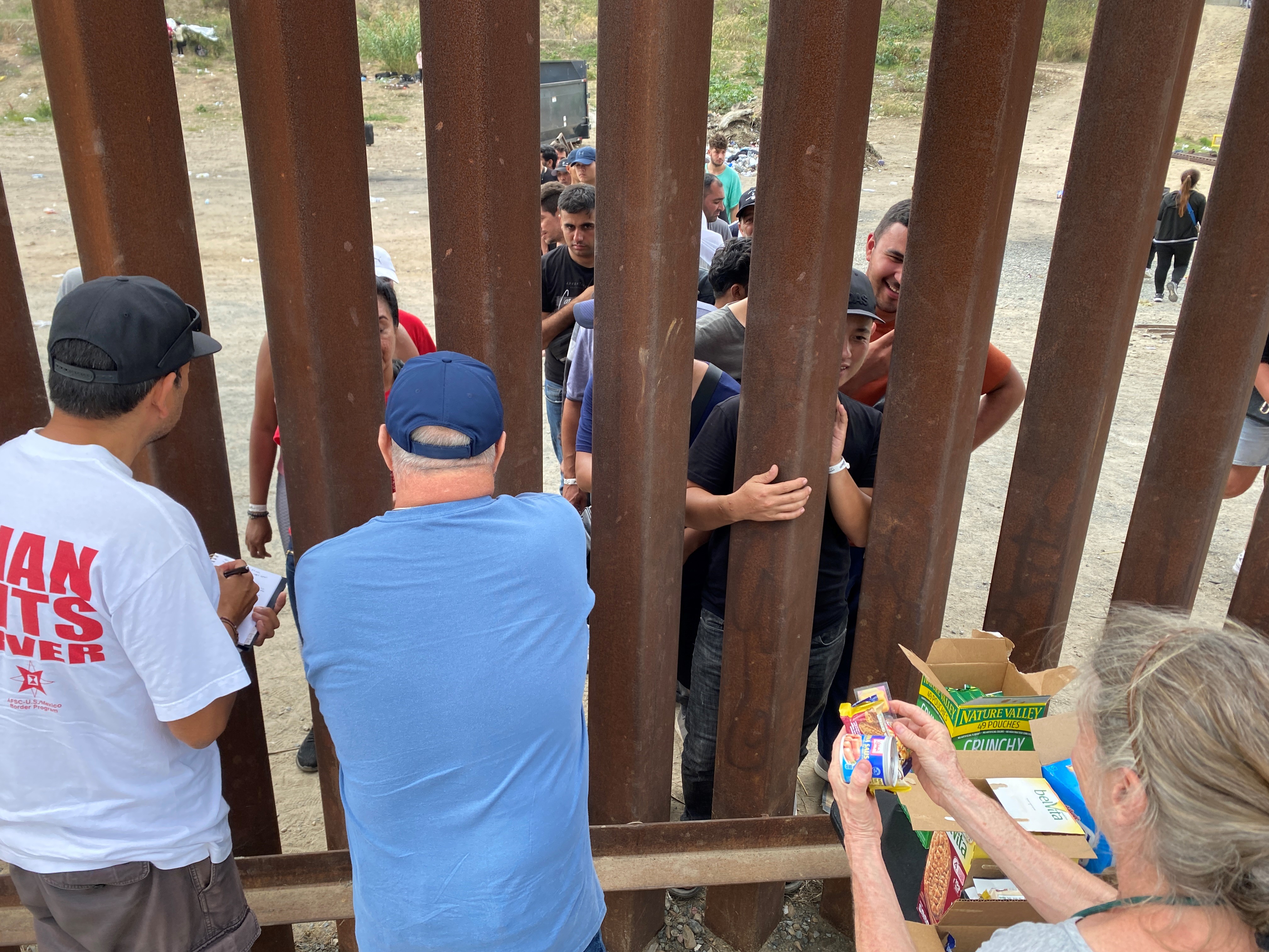 Humanitarian activists distribute snacks and other goods to asylum-seeking migrants at the U.S.-Mexico border south of San Diego on Sept. 12, 2023.