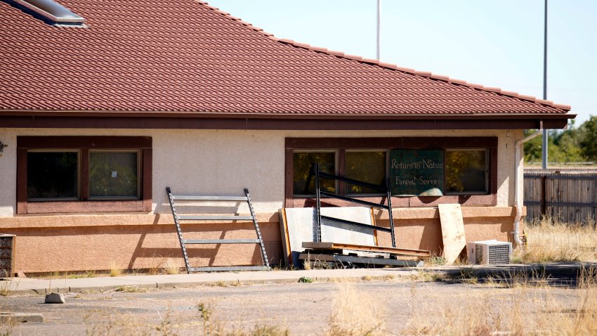 A sign covers the broken back window of the Return to Nature Funeral Home