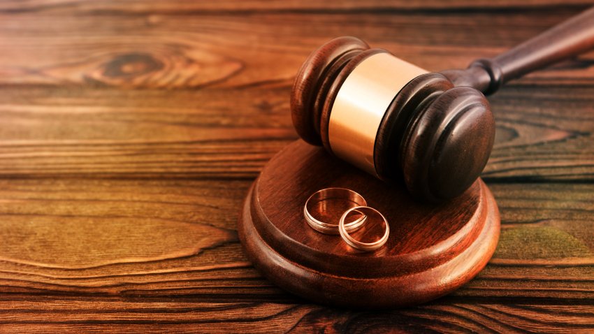 a pair of gold wedding rings, a judge’s hammer on a wooden table background. family law