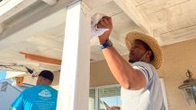 A volunteer helps paint a home's porch for Christmas in October. Oct. 28, 2023. 