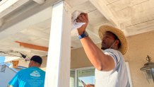A volunteer helps paint a home's porch for Christmas in October. Oct. 28, 2023.