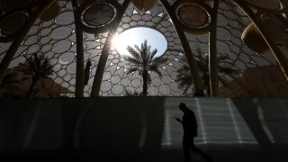 An attendee checks a smartphone whilst walking past Al Wasl dome in the Blue Zone ahead of the COP28 climate conference at Expo City in Dubai, United Arab Emirates, on Wednesday, Nov. 29, 2023. More than 70,000 politicians, diplomats, campaigners, financiers and business leaders will fly to Dubai to talk about arresting the world’s slide toward environmental catastrophe.