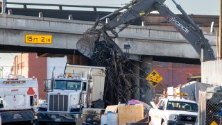 Workers remove burned debris from under the 10 Freeway.