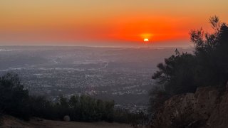 The sun sets in bright orange hues as seen from Cowles Mountain in San Diego, Calif., Sunday, Oct. 29, 2023, (NBC 7)