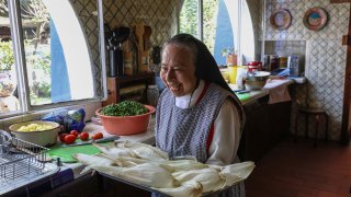 Nun Maria Ines Maldonado, 76, carries a tray of corn husks stuffed with shredded chicken and salsa verde at the Convent of the Mothers Perpetual Adorers of the Blessed Sacrament in Mexico City, Friday, Dec. 1, 2023.